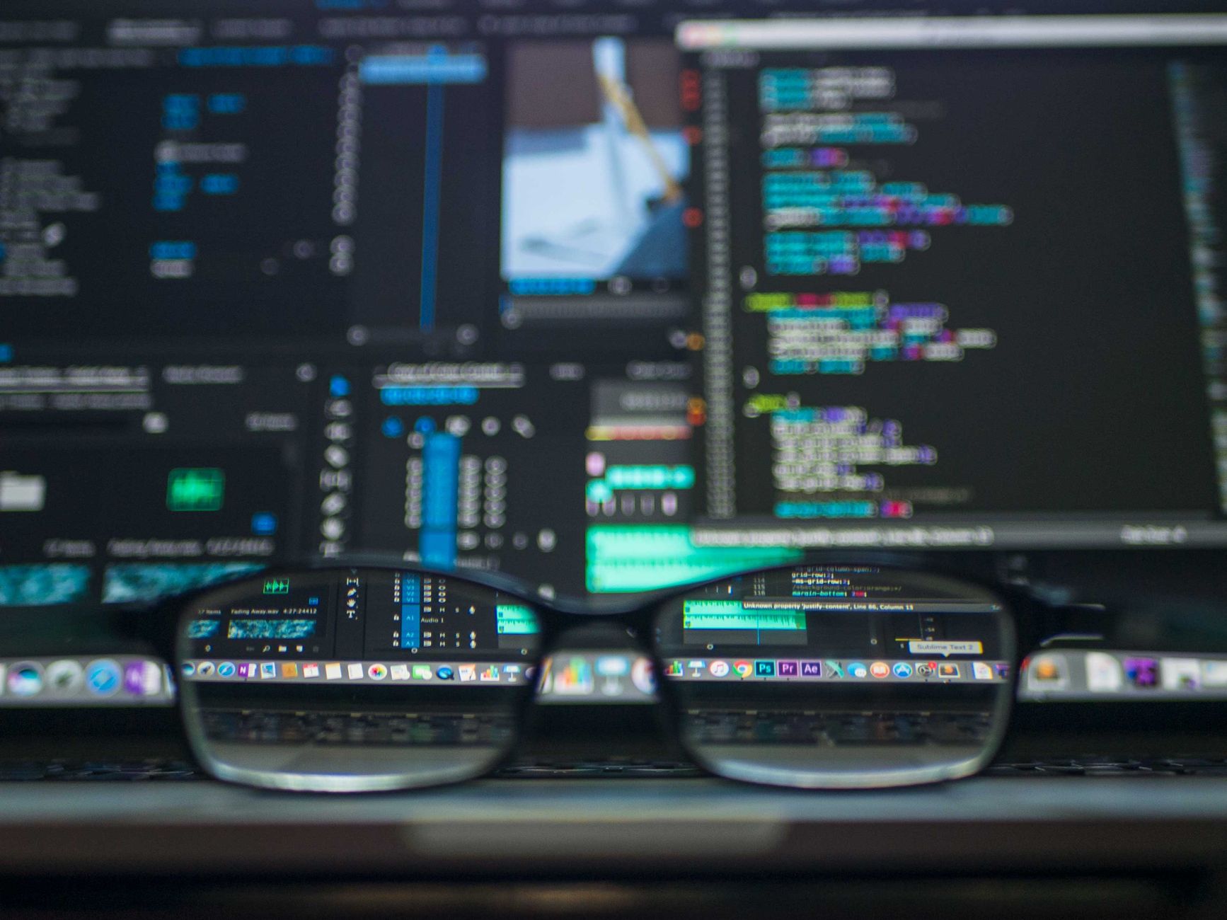 Okulary odbijające kod komputerowy na monitorze w ciemnym otoczeniu